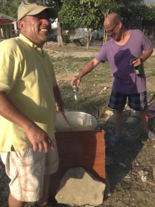Miguel's neighbor Antonio stirs the Natilla while his other neighbor adds some Aguardiente